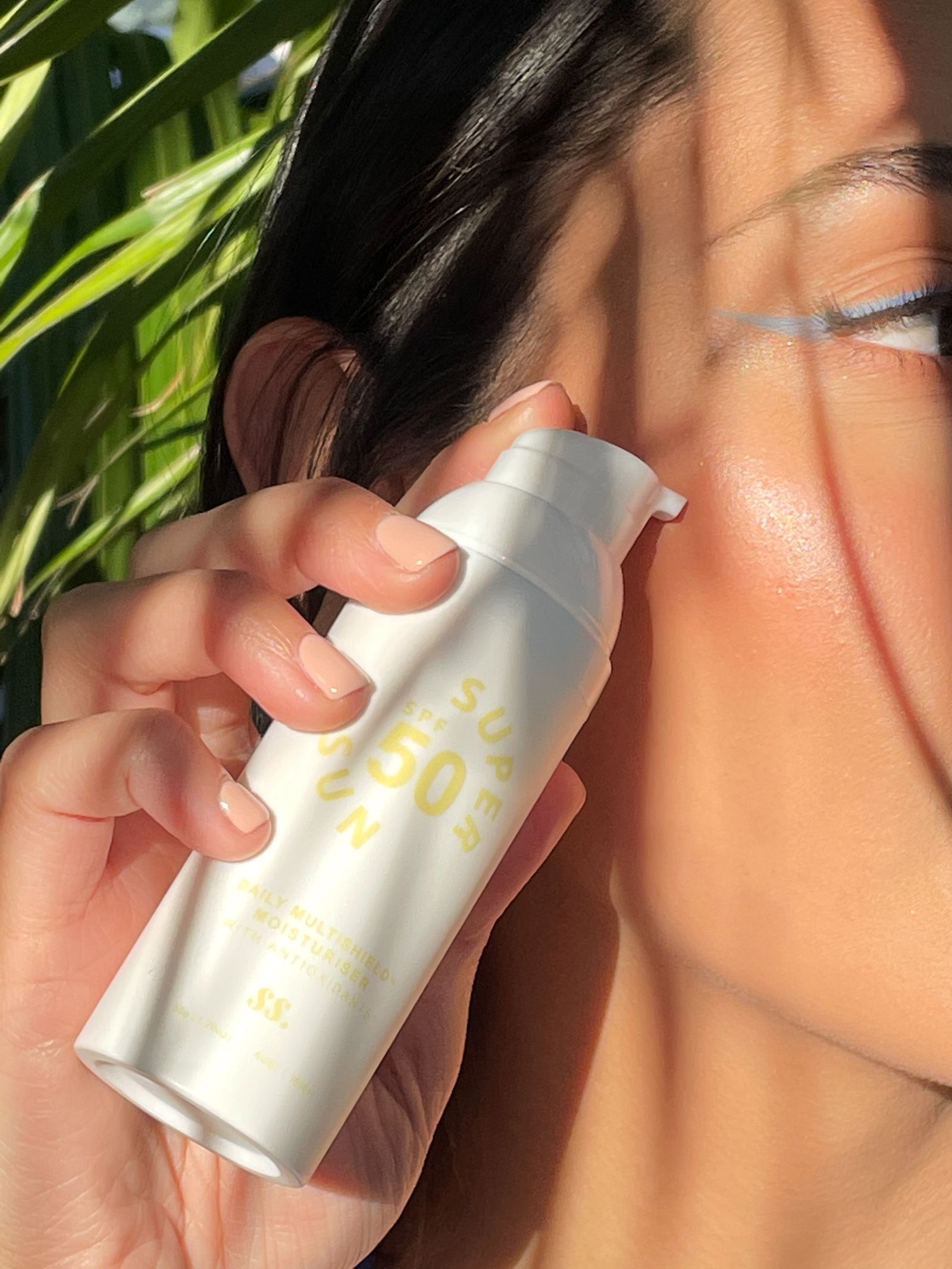 Woman holding SPF 50 sunscreen in warm summer light